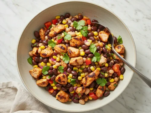 Top-down close-up of the finished Grilled Chipotle Chicken and Corn Dense Bean Salad in a serving bowl, garnished with cilantro.