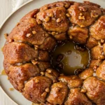 Close-up top-down view of the finished Easy Monkey Bread on a serving plate, showing golden brown, glazed pull-apart pieces, looking sticky, natural, and home-baked.