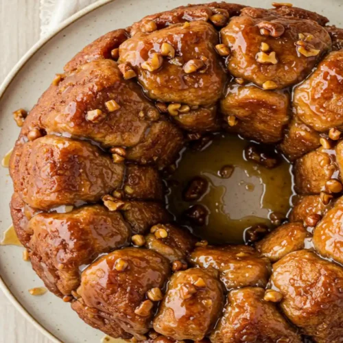 Close-up top-down view of the finished Easy Monkey Bread on a serving plate, showing golden brown, glazed pull-apart pieces, looking sticky, natural, and home-baked.