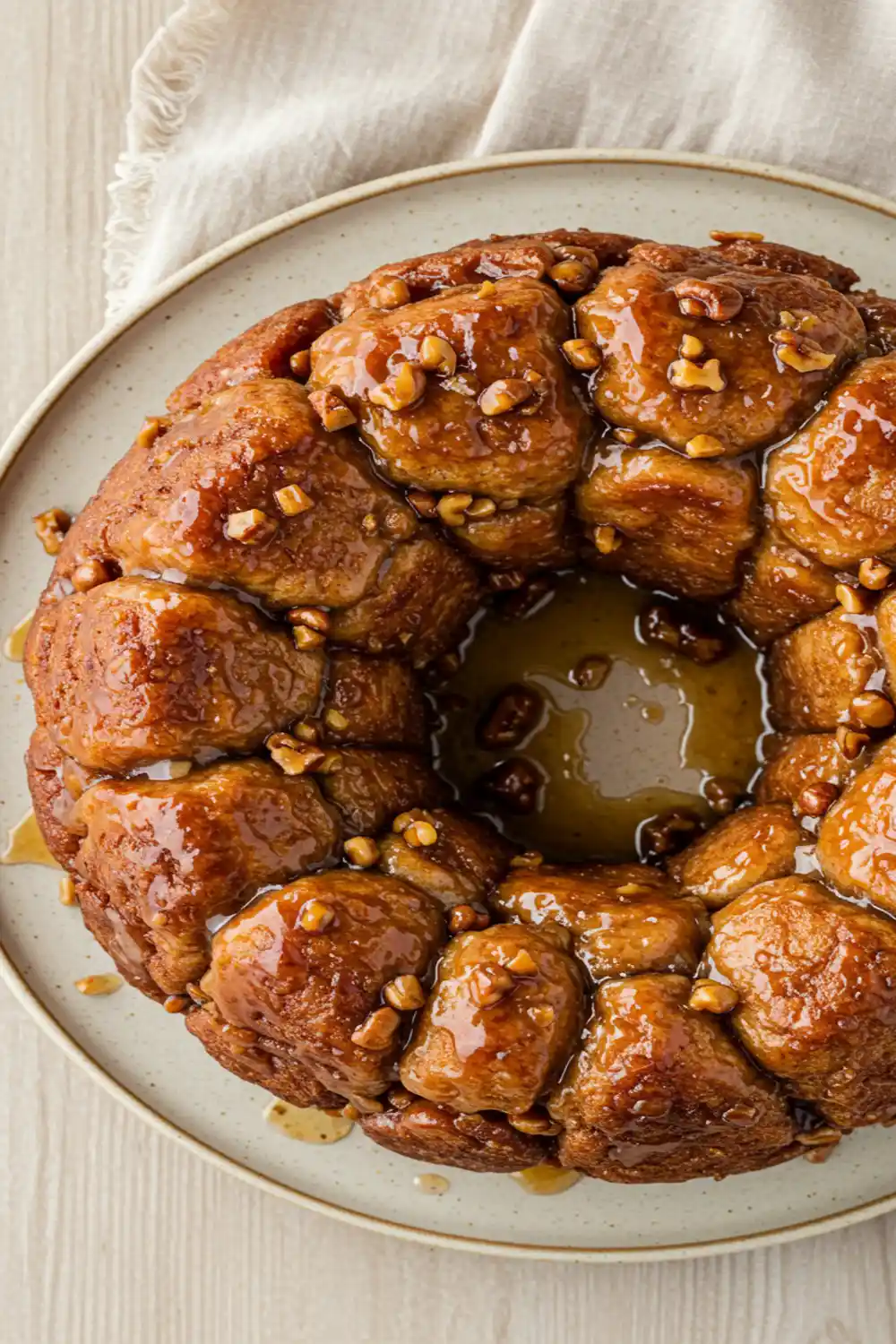 Close-up top-down view of the finished Easy Monkey Bread on a serving plate, showing golden brown, glazed pull-apart pieces, looking sticky, natural, and home-baked.